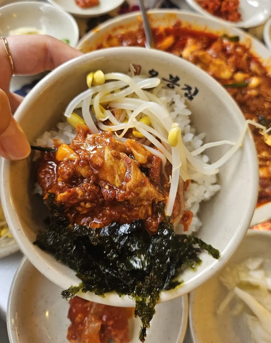 A spoonful of octopus bibimbap topped with seaweed flakes