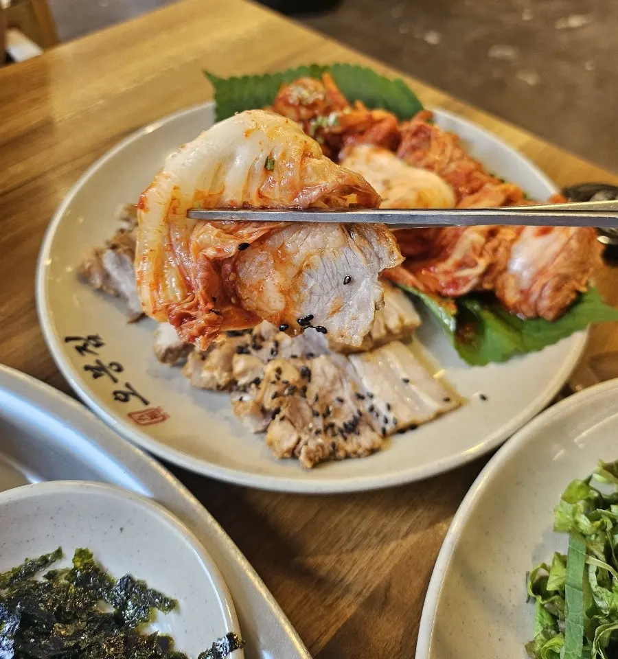 A wrap of bossam meat topped with cabbage kimchi