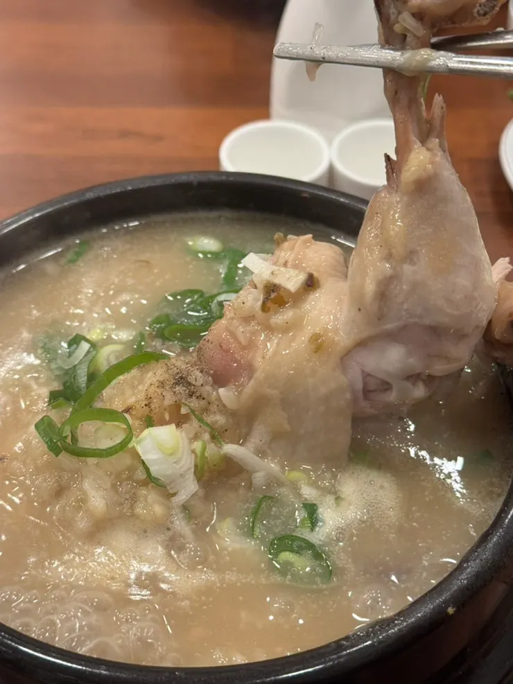 A cup of ginseng wine placed alongside the samgyetang
