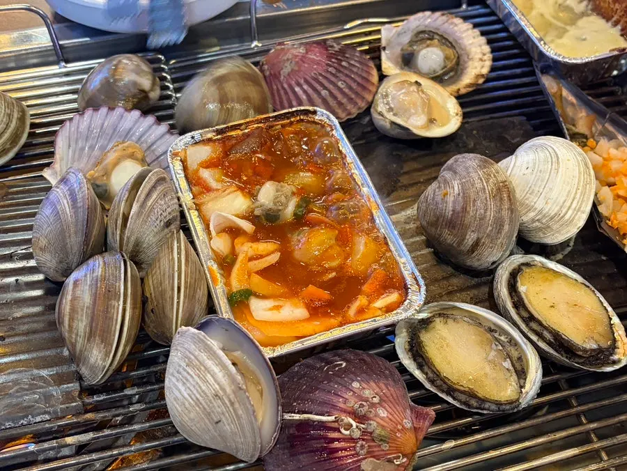 A big open clam and tteokbokki in a small metal pot