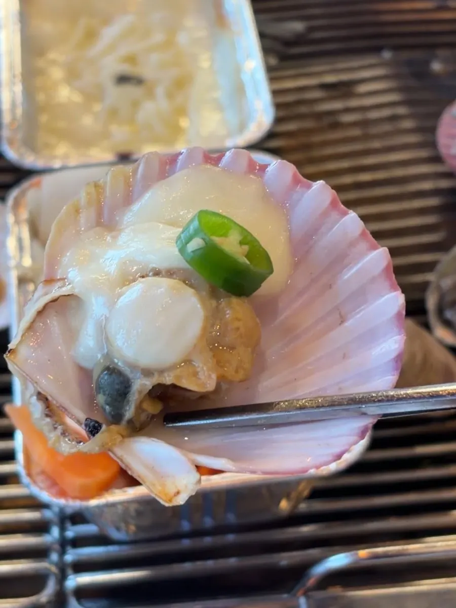 A piece of grilled clam topped with mozzarella cheese