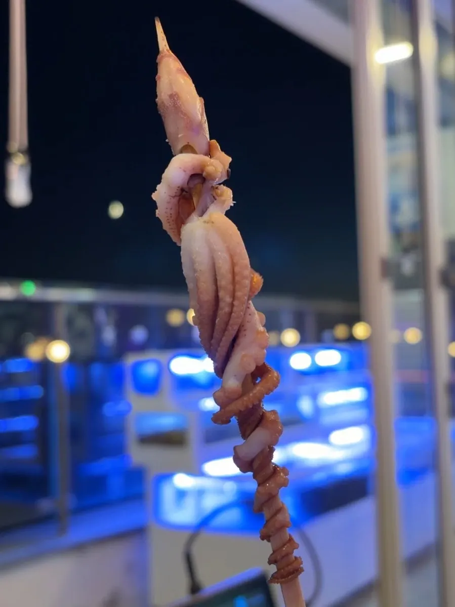 Rolled-up octopus skewers grilling