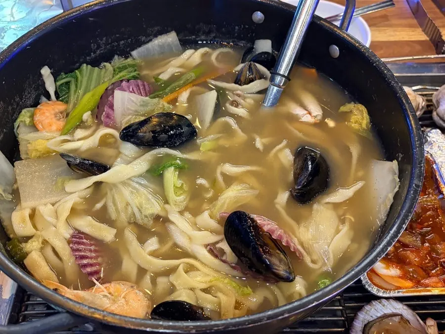 A pot of seafood kalguksu packed with seafood