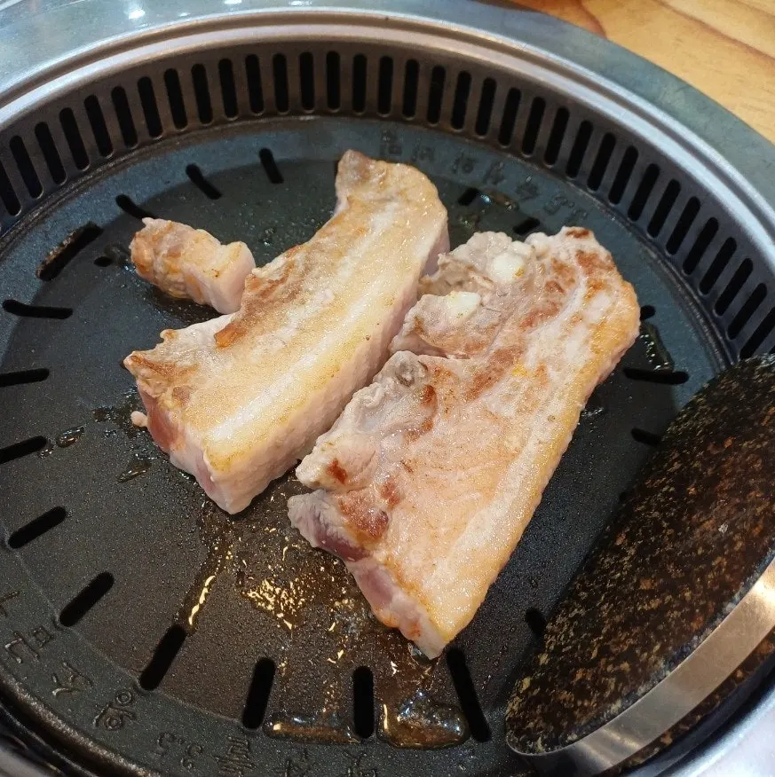 Pork belly grilled by staff with pickled side dishes on top