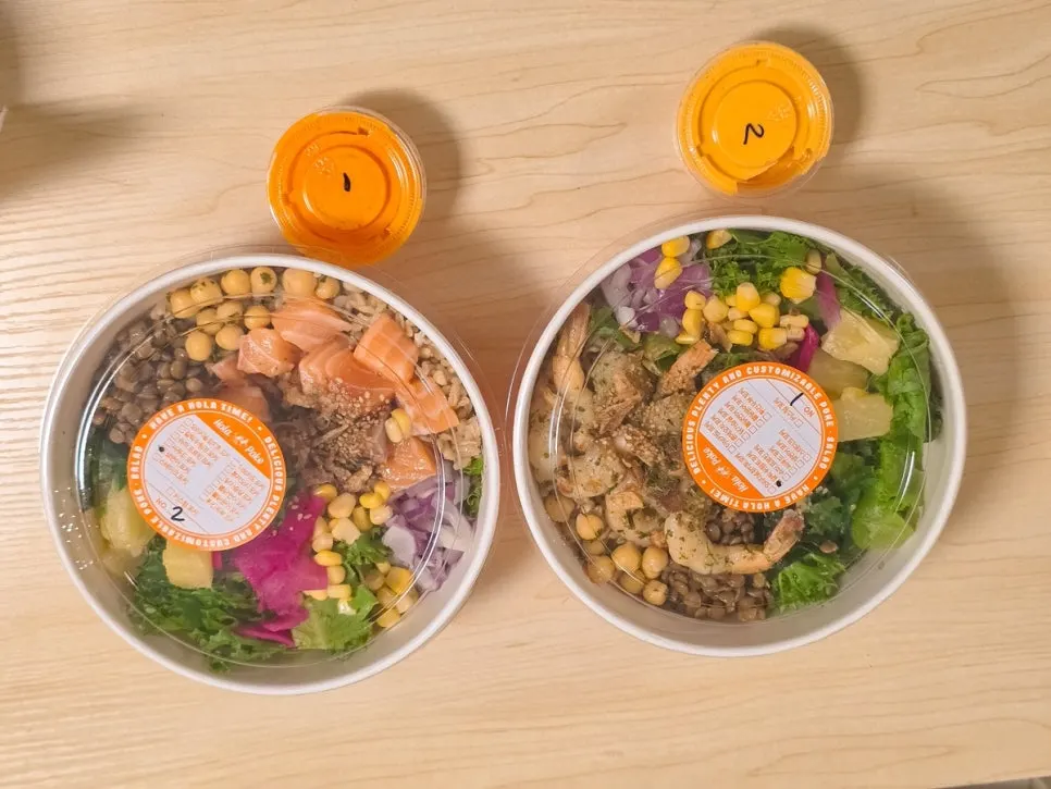 Two takeout poke bowls laid out at home