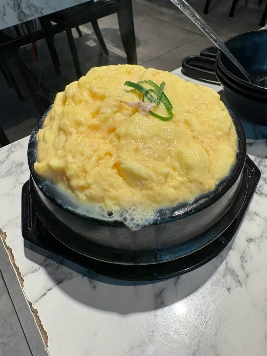 A bite of pork belly with ssamjang on baek kimchi