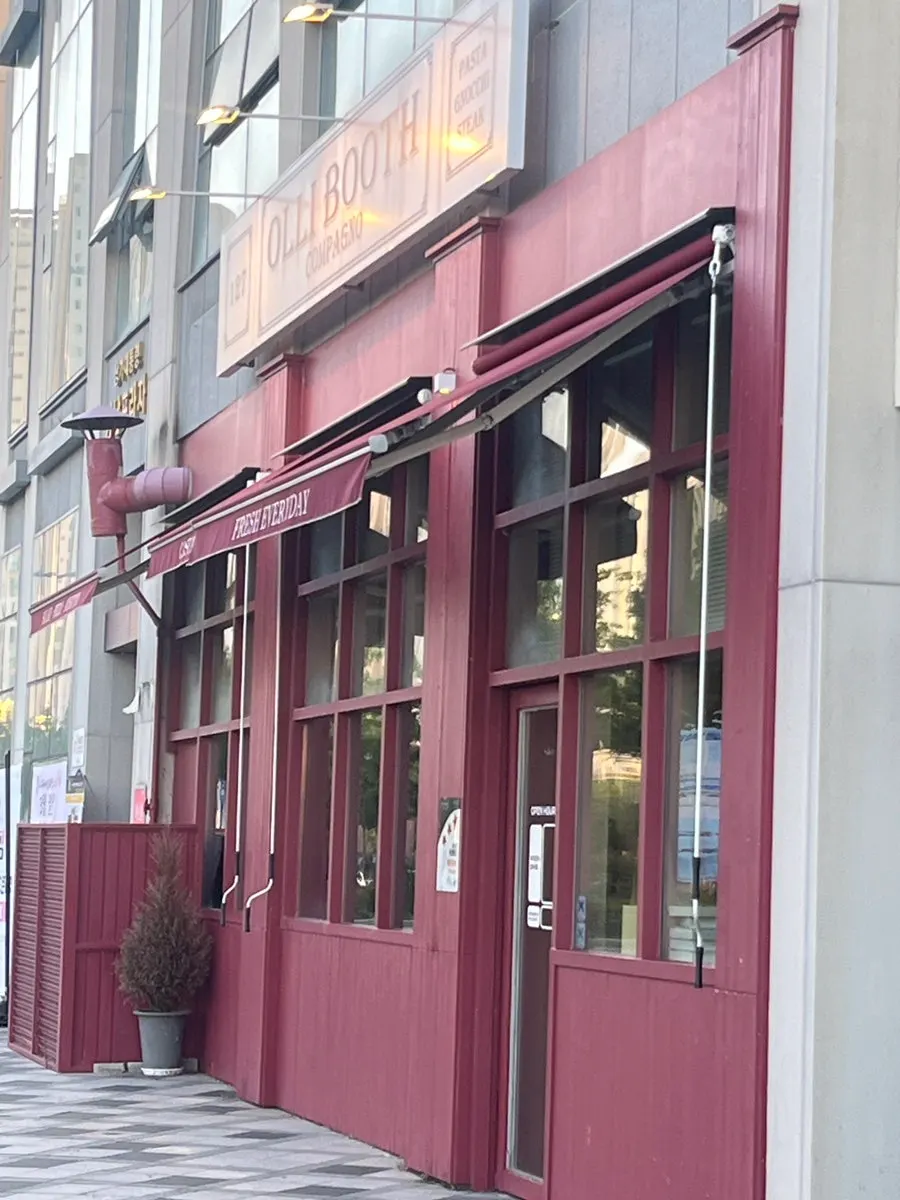 Storefront with the red door and sign visible