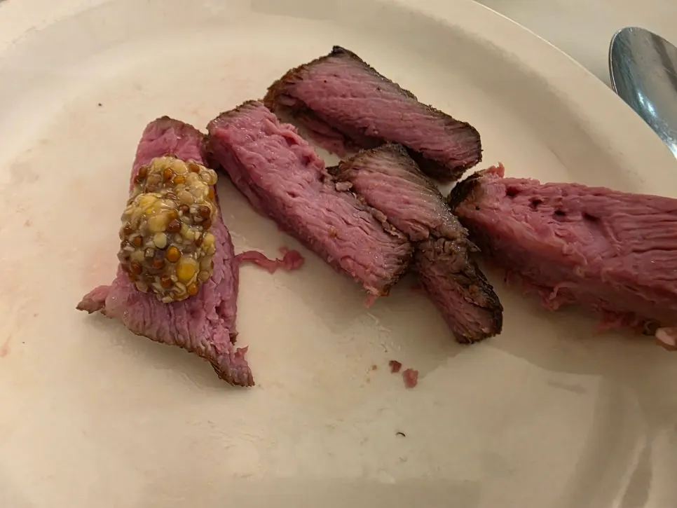 A piece of hanger steak topped with whole grain mustard