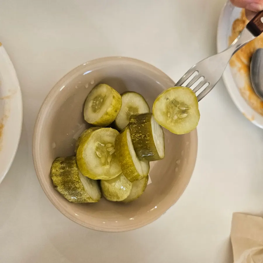 Cucumber pickles served alongside the pasta