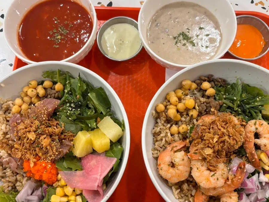 The table setting with two poke bowls, tomato soup, and mushroom soup