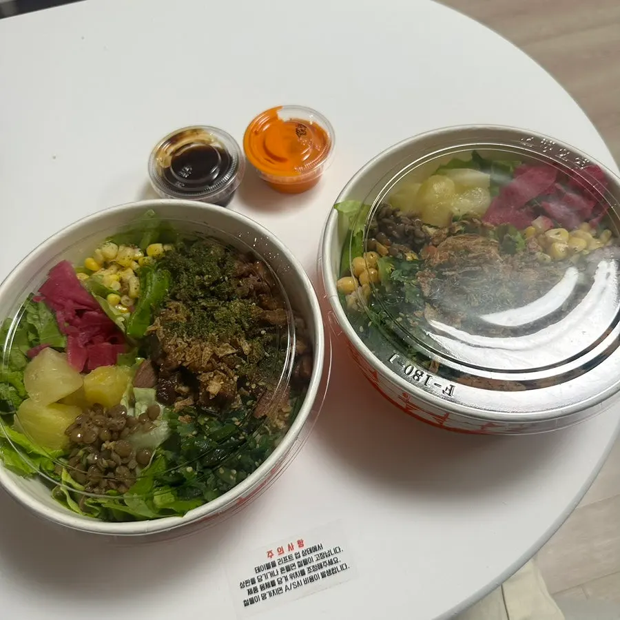 Opened takeout containers of smoked duck poke and garlic shrimp poke