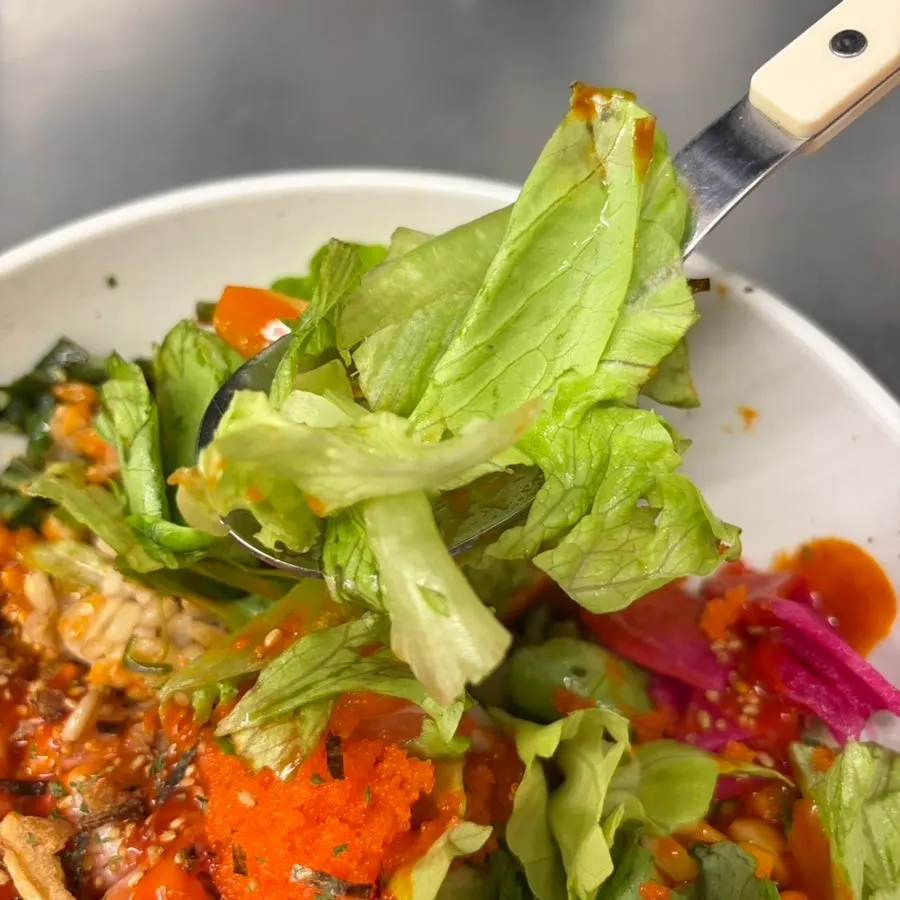 A bite of buldak salmon poke topped with flying fish roe
