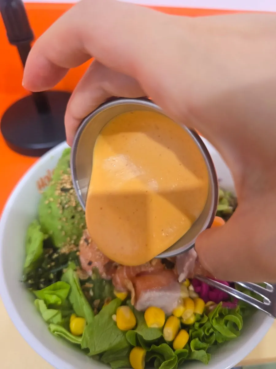 A bite of salmon dipped in sriracha mayo