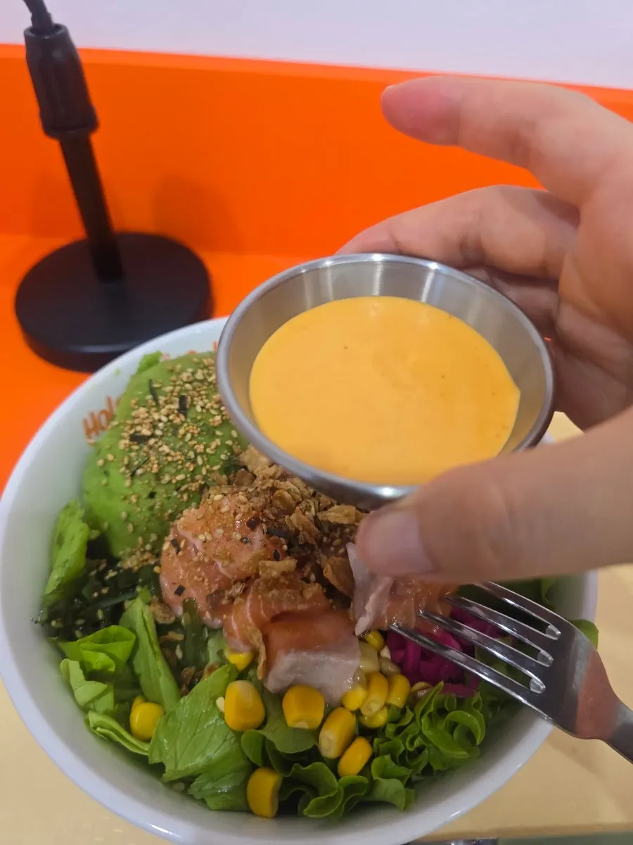 A bite of poke topped with brown rice and vegetables