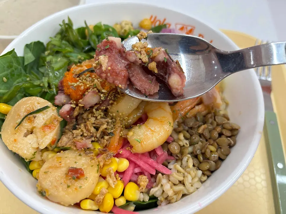 Close-up of seafood poke showing octopus, scallop, and shrimp