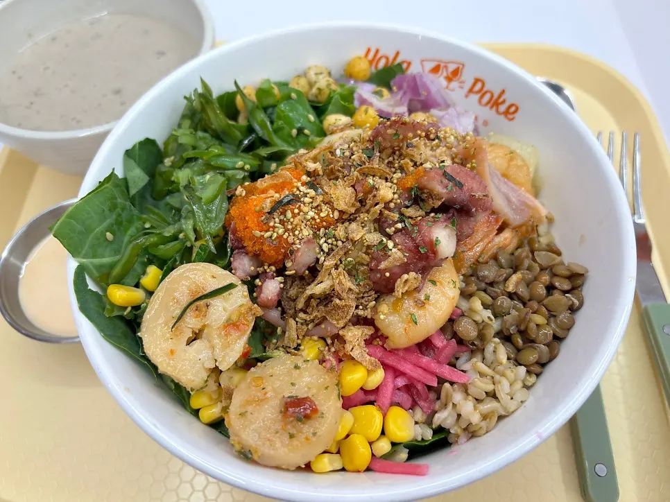 A poke bowl mixing brown rice, vegetables, and seafood