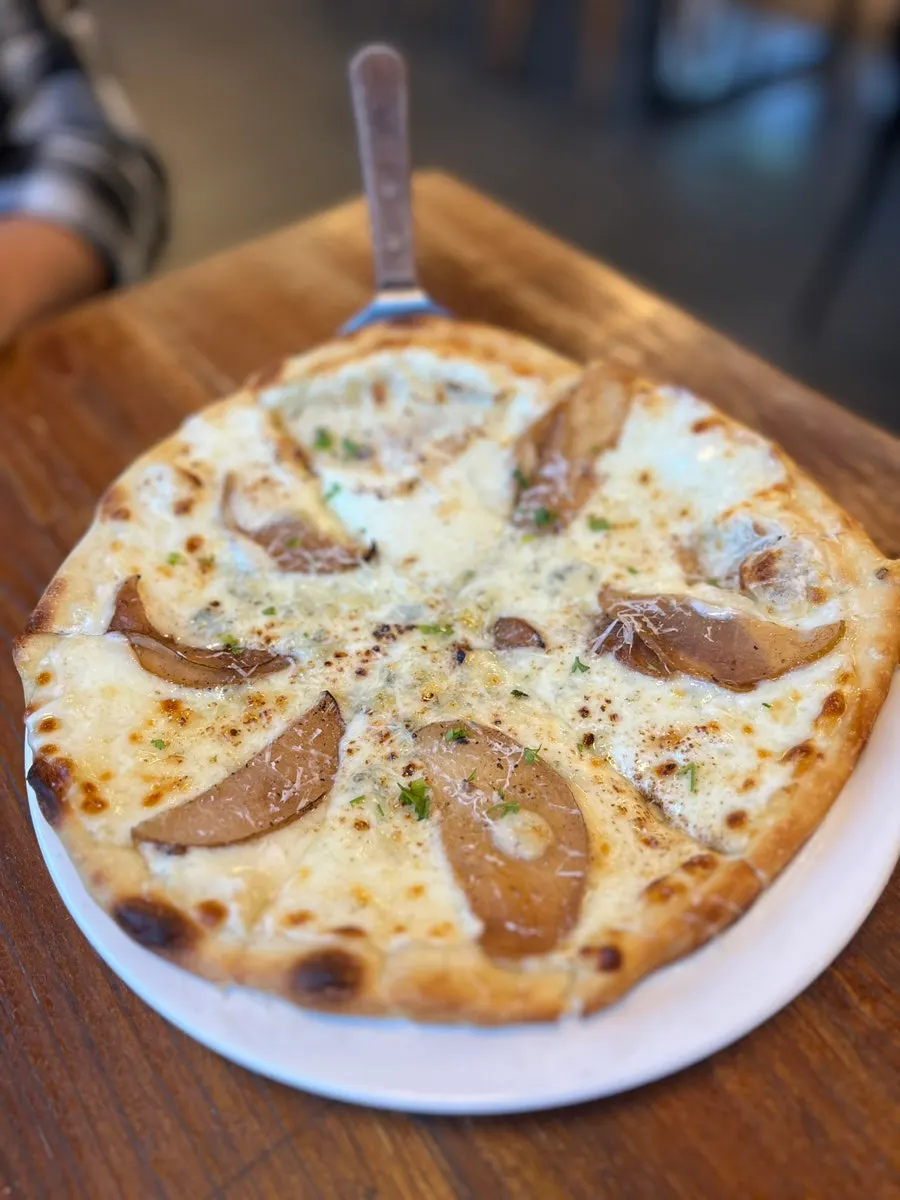 Meja dengan pizza dan pasta yang dipesan