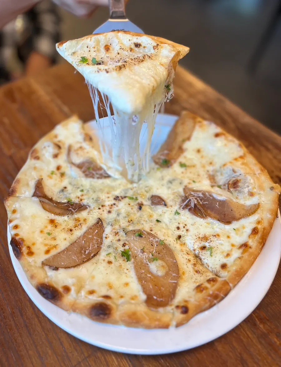 Sepotong pizza gorgonzola dengan keju yang melar