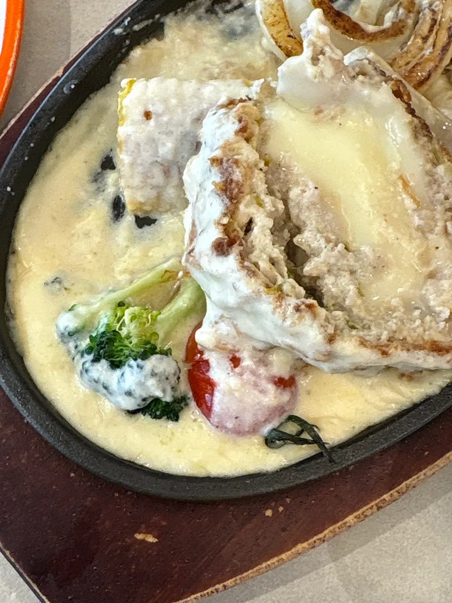 Leftover cheese and cutlet pieces on the iron plate