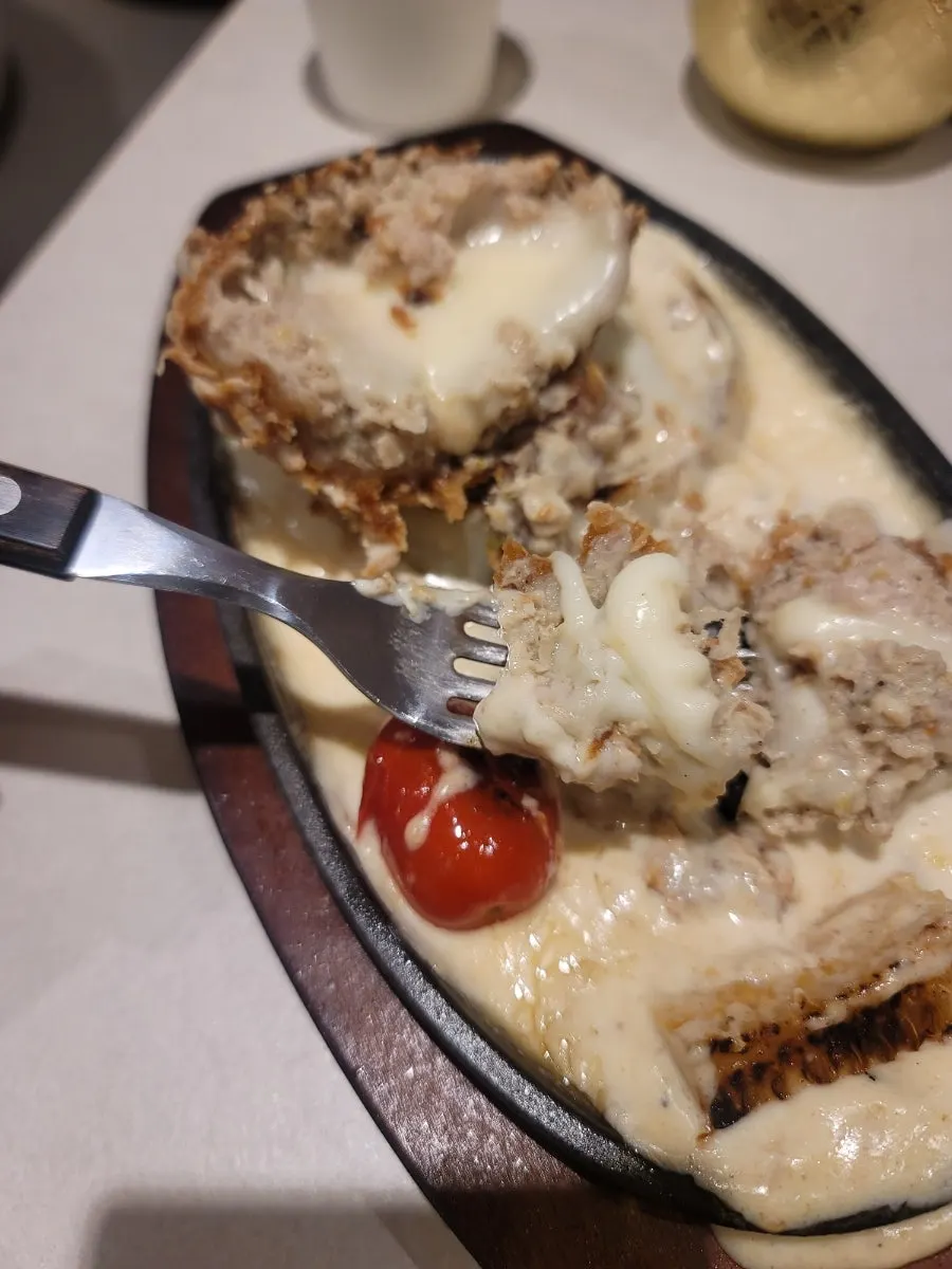 치즈를 늘려 올린 철판치즈카츠 한 조각
