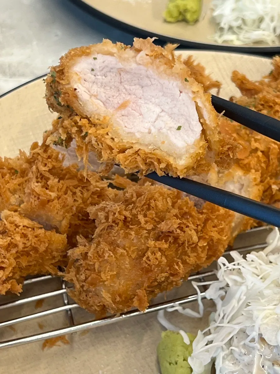 A piece of tenderloin katsu picked up with chopsticks
