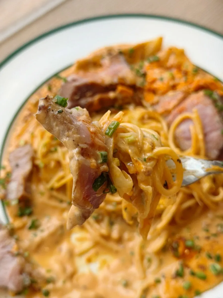 Noodles and meat lifted together on a fork