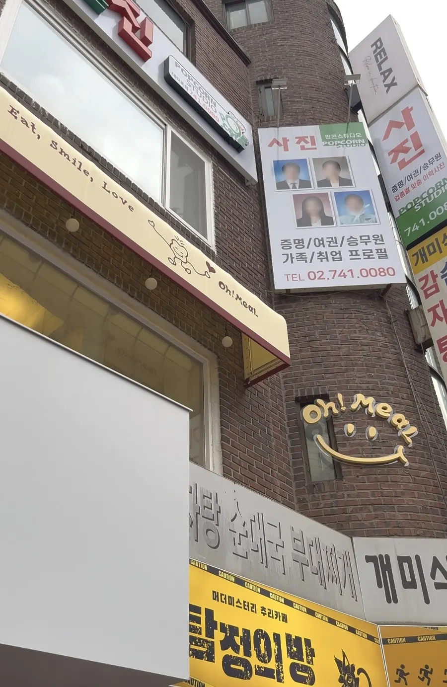 벽돌 외벽에 노란 차양이 걸린 오밀 혜화 대학로 건물 외관