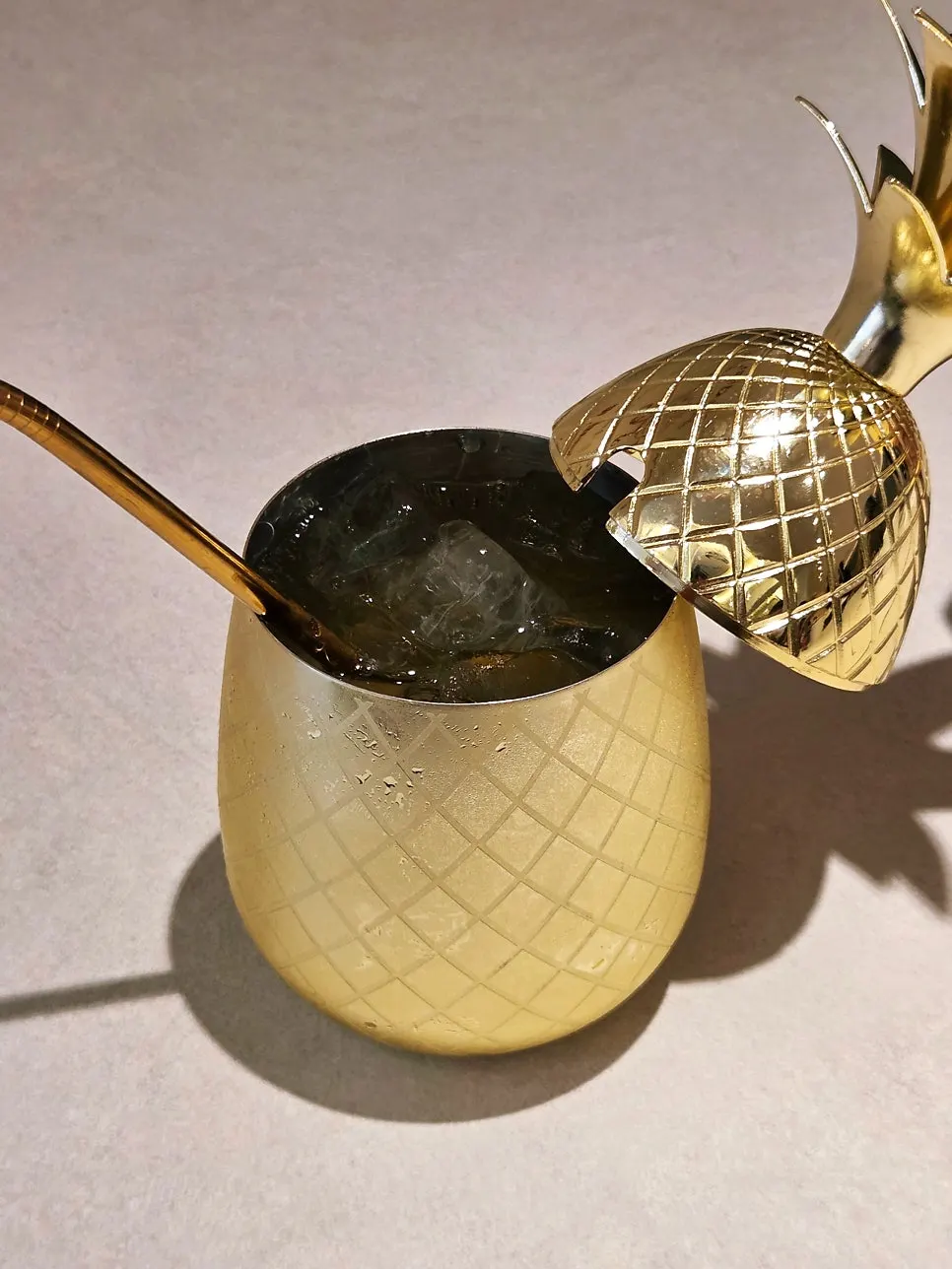 The pineapple ade with its lid opened, showing ice inside