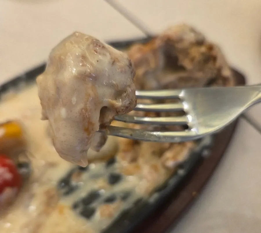 A piece of katsu dipped in melted cheese