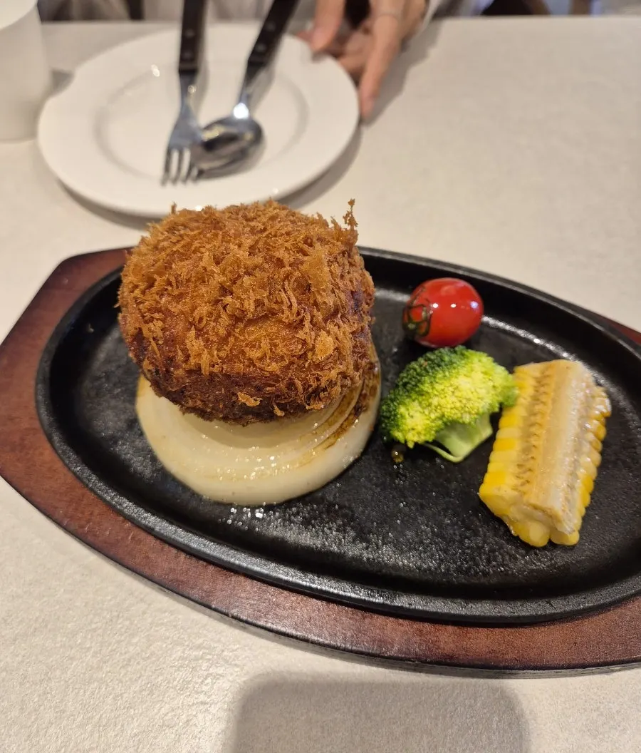 Sizzling cheese cutlet with cheese poured over a hot griddle