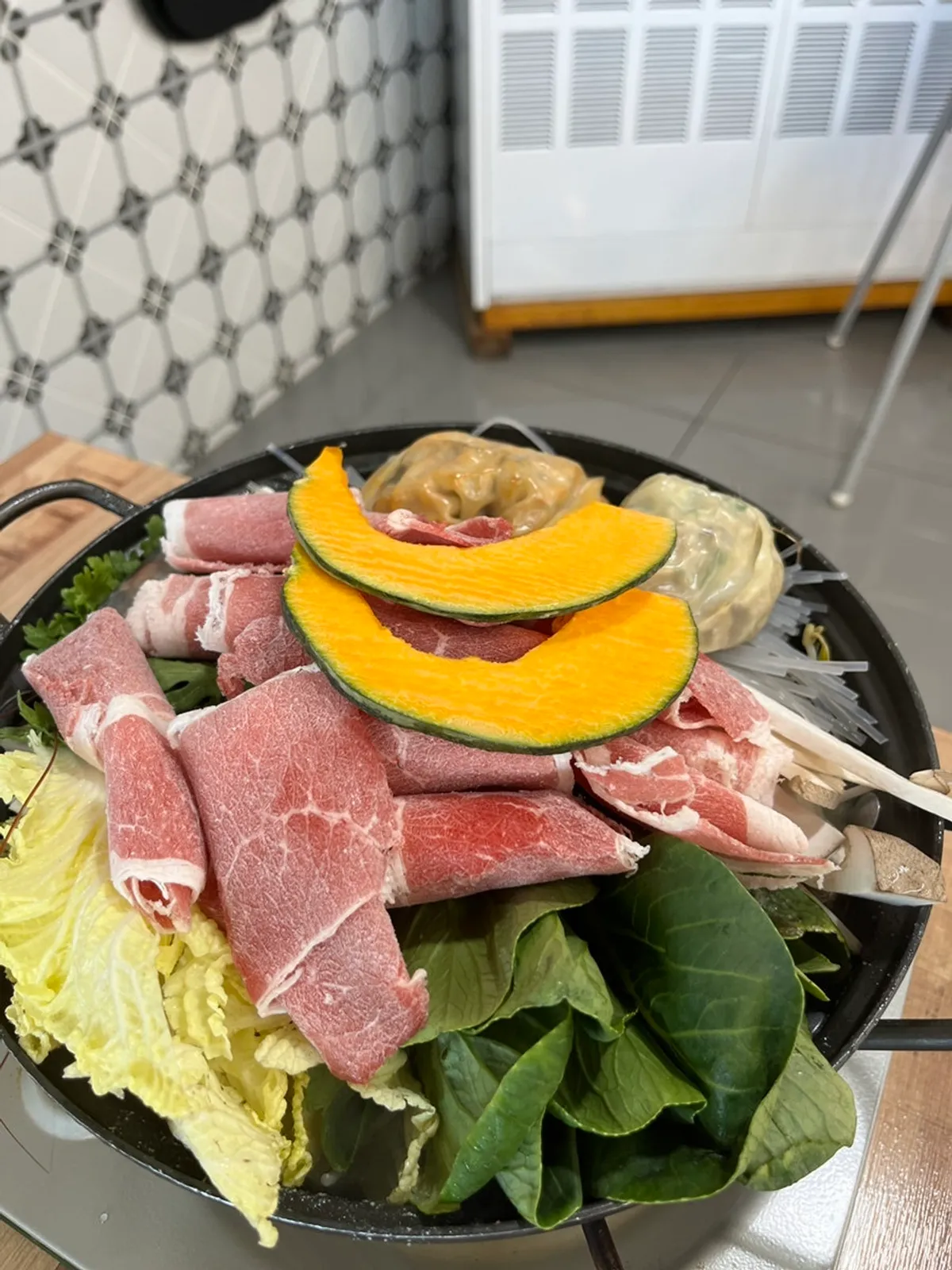 Pot of handmade dumpling hot pot loaded with vegetables, glass noodles, and meat