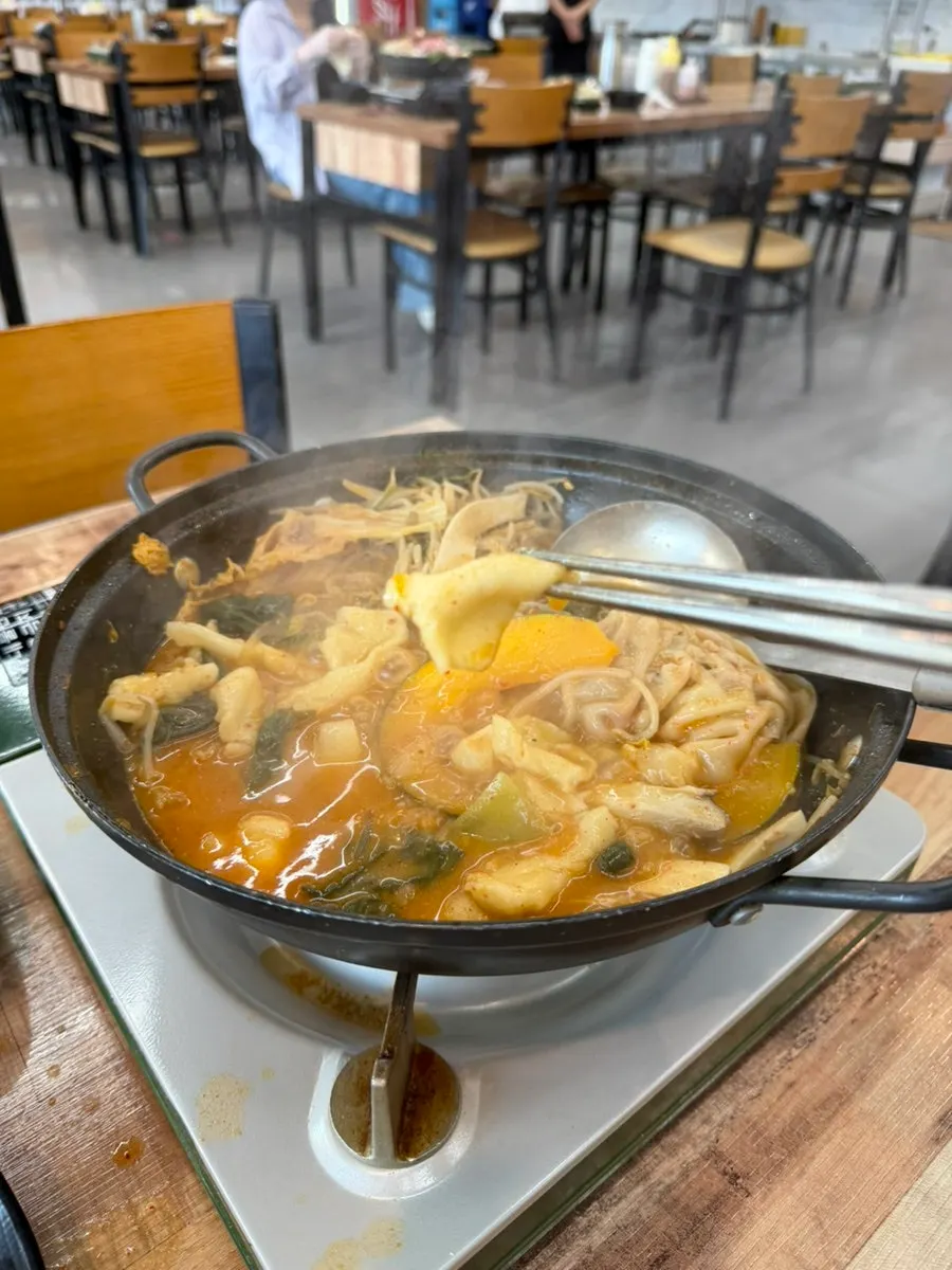 A scoop of dumplings and vegetables with broth