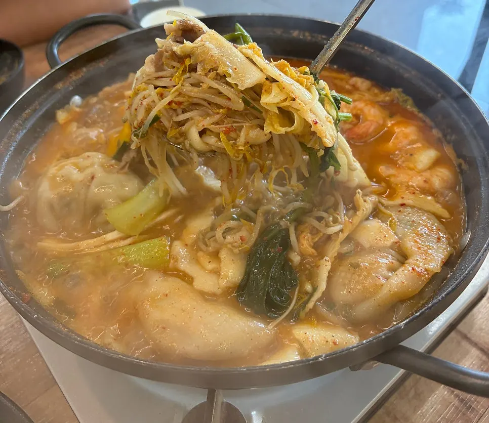 Hot pot broth loaded with bean sprouts, cabbage, and mushrooms