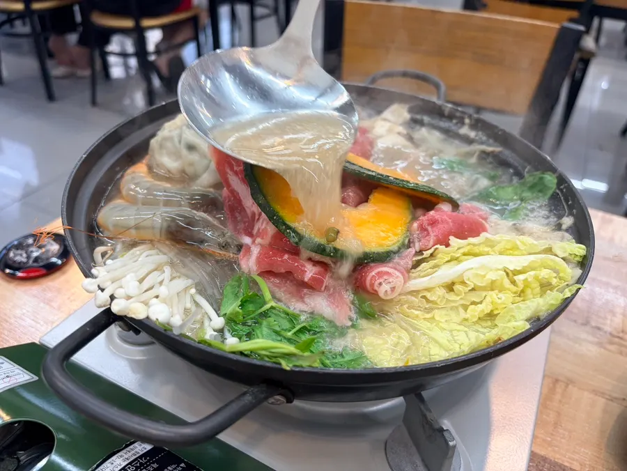 Ladling broth over the dumpling hot pot