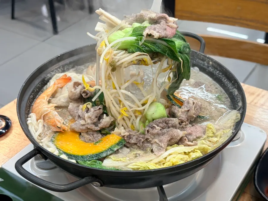 Bean sprouts, bok choy, and meat cooking in the hot pot