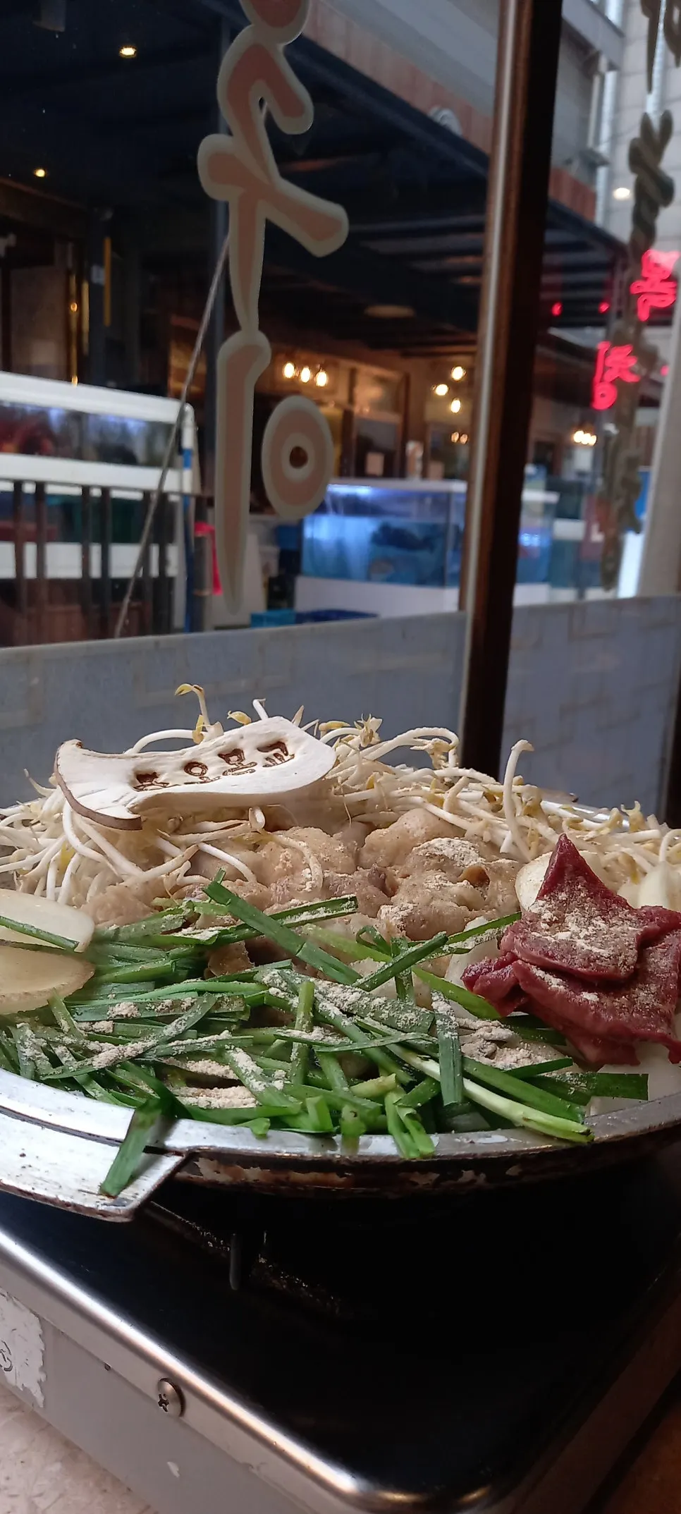 Garlic gopchang grilling on the griddle with bean sprouts, chives and onion