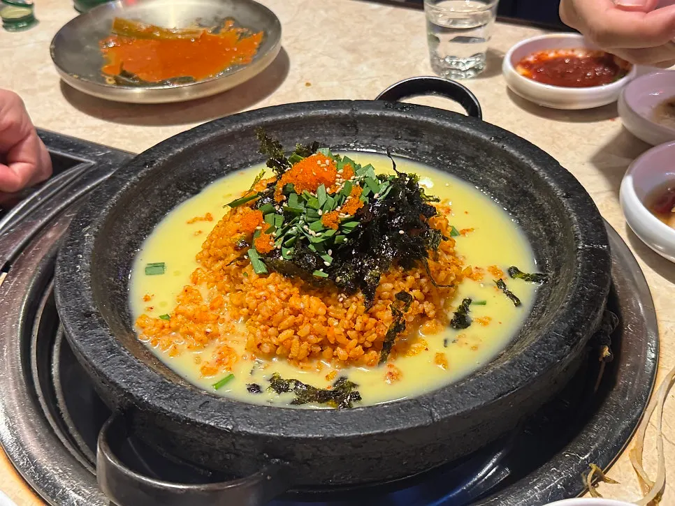 A bite of gopchang topped with green onion kimchi