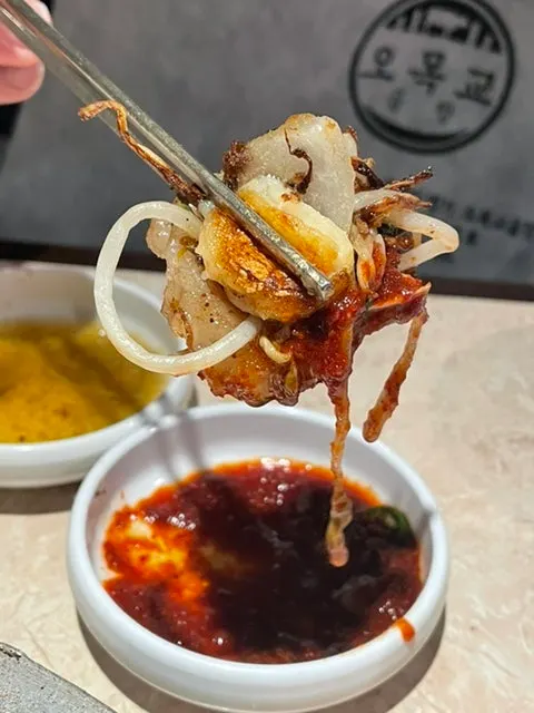 A grilled piece of gopchang dipped in sauce