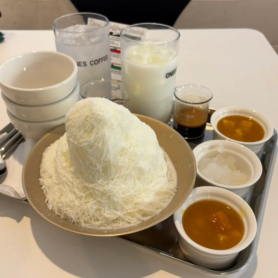 Mango bingsu and two iced coffees served at the table
