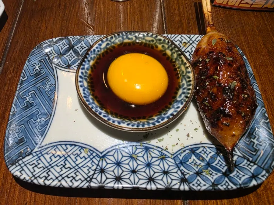 Eggplant-chicken skewer being dipped in sauce