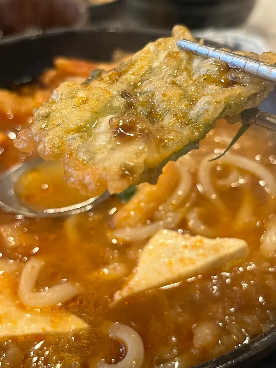 Dipping tempura into the spicy tempura kimchi nabe