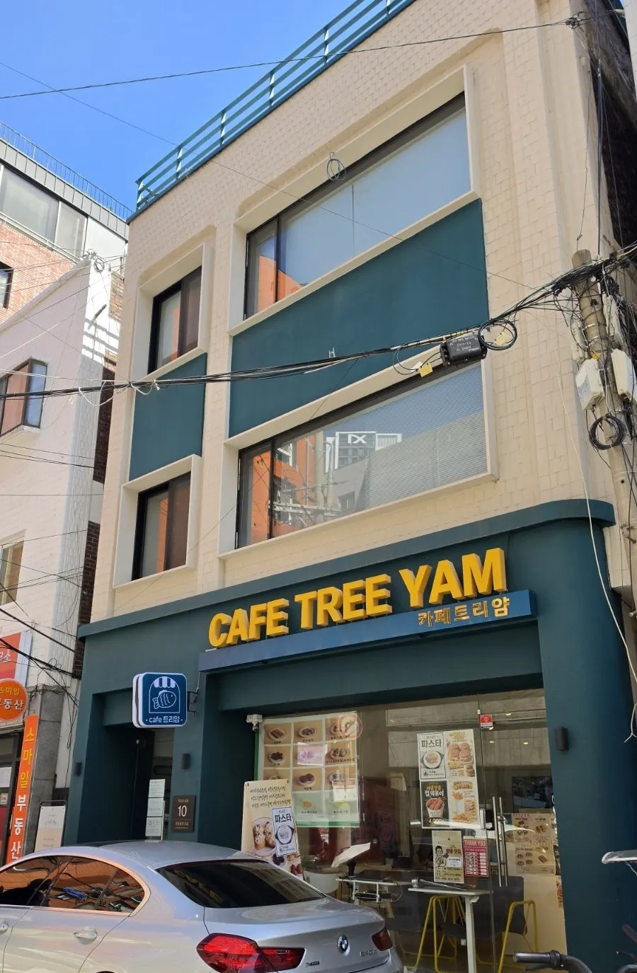 Exterior of the green building with a café on the first floor