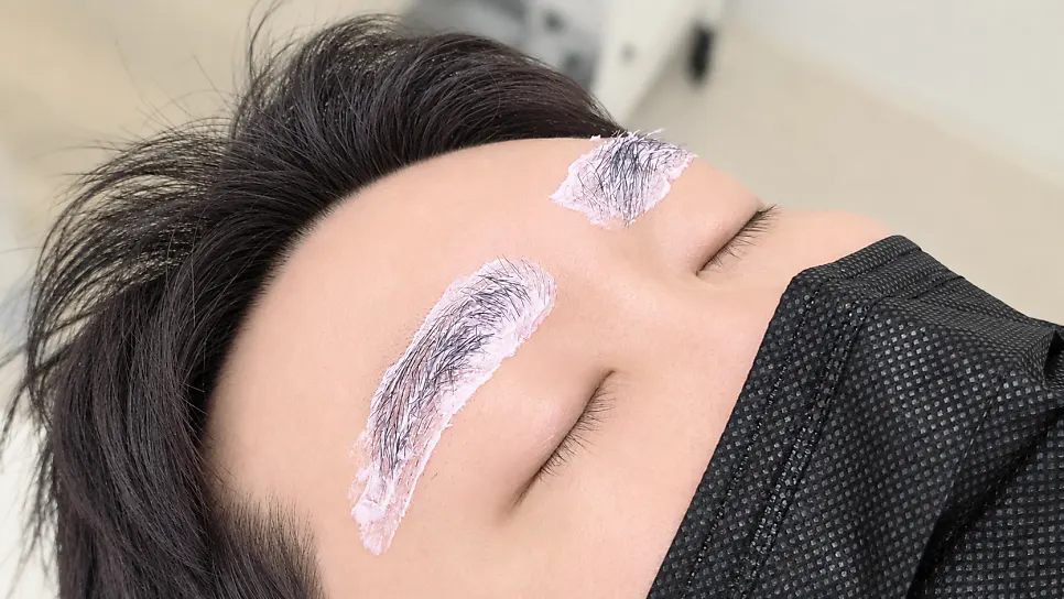 Applying numbing cream to the eyebrows