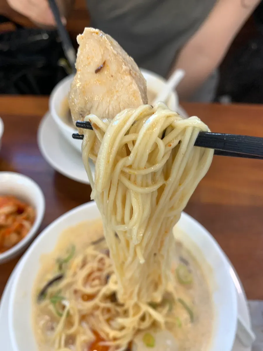 Reddish seasoning visible beneath the foamy karai paitan broth