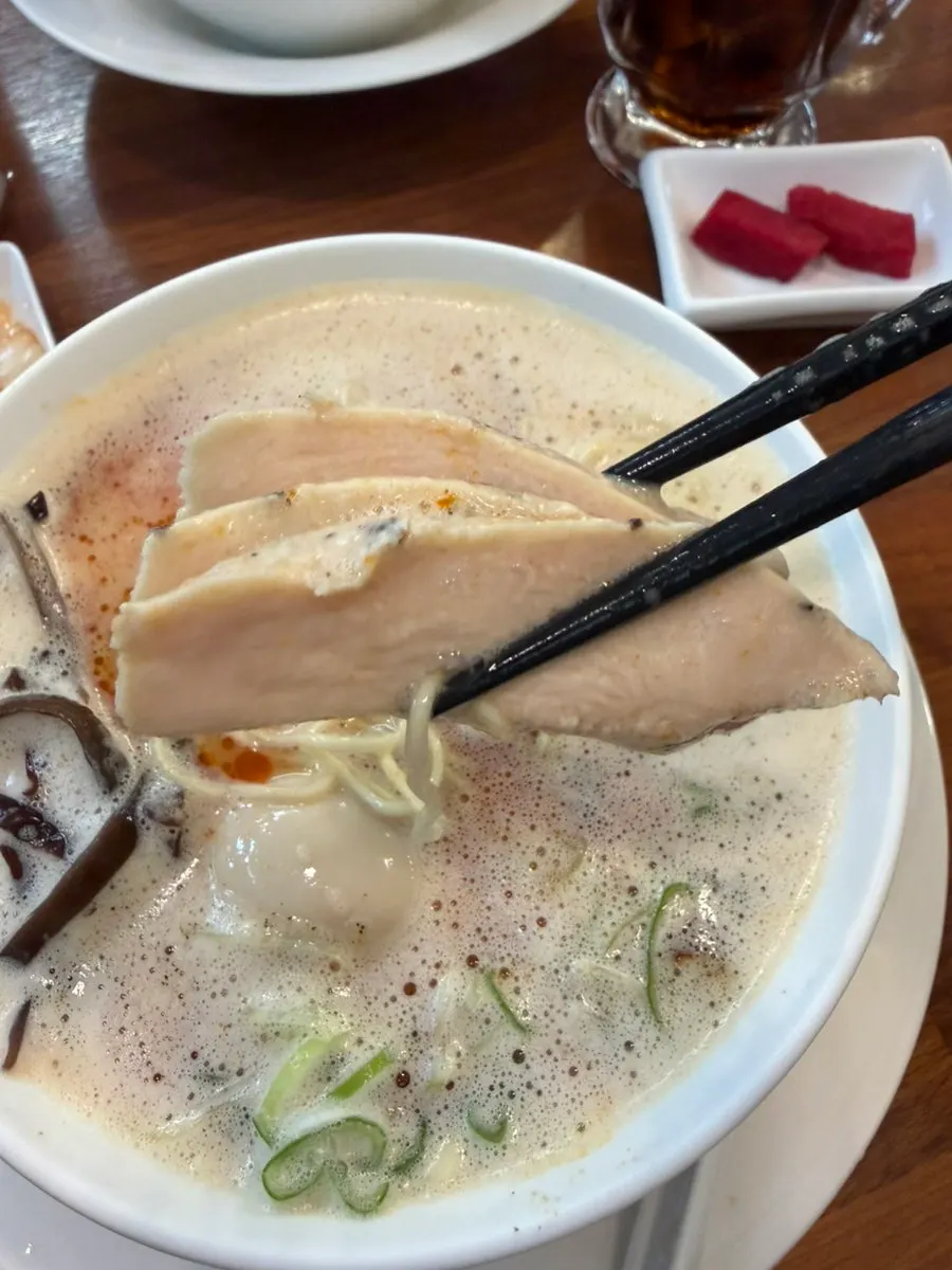 Thin Japanese-style ramen noodles lifted with chopsticks