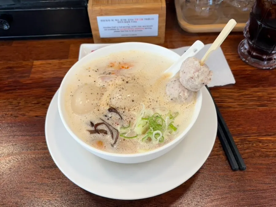 Cola poured into an ice-filled highball glass next to ramen