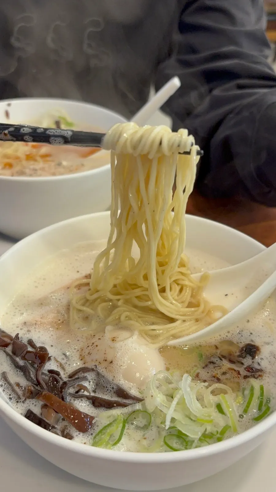 Two bowls of ramen topped with foam, tori paitan and karai paitan