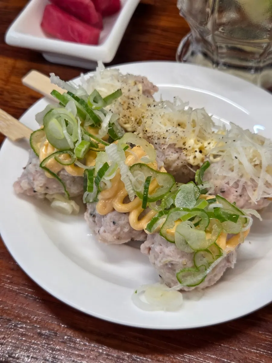 Bite-sized tsukune pieces being picked up
