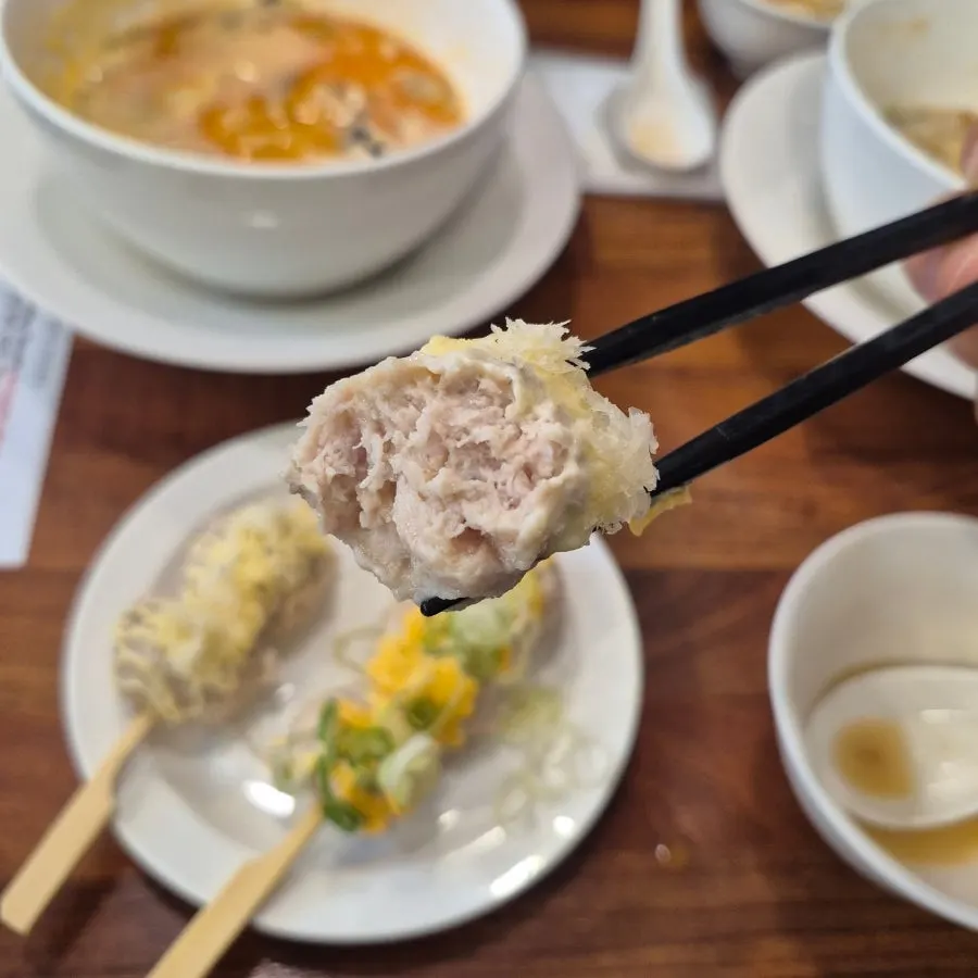 A piece of tsukune topped with cheese sauce