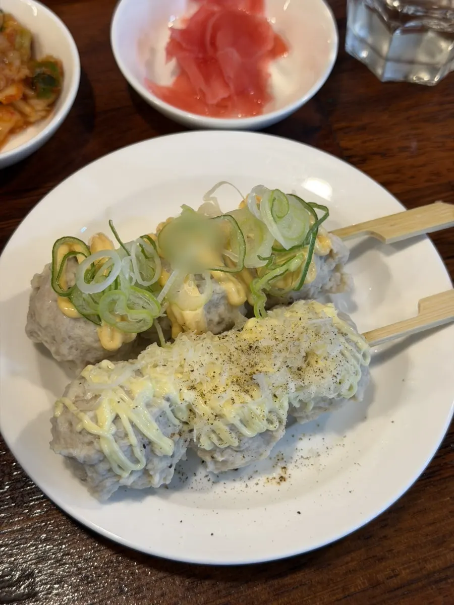 A plate of mixed tsukune topped with cheese and green onion